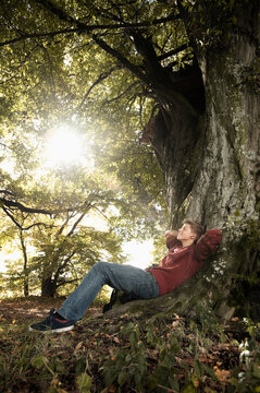 Man lying on forest floor with sunlight through trees
