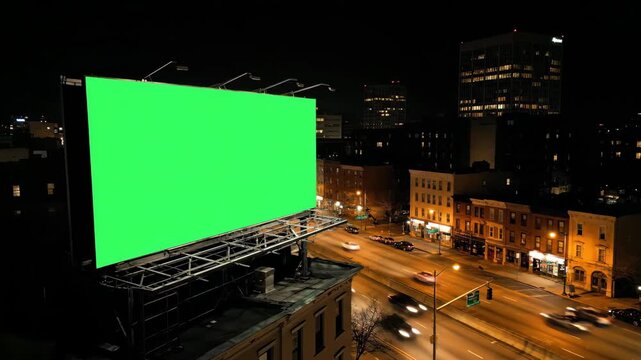 Green screen billboard blank hoarding on a city rooftop at night with fast moving traffic light trails for advertising mockup commercial promotion and media copy space