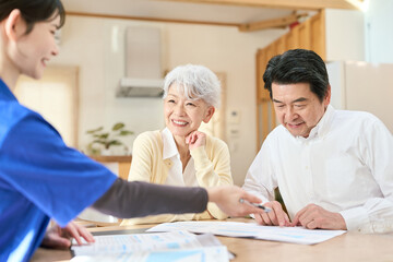 Obraz premium 訪問介護でプランの説明を聞くシニア夫婦