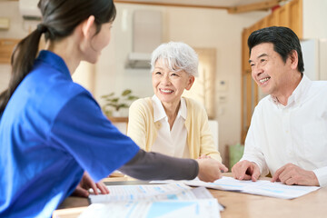 Obraz premium 訪問介護でプランの説明を聞くシニア夫婦