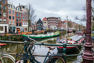 Amsterdam canal presenting traditional dutch architecture, houseboats moored along the waterway, and a bicycle parked on a bridge, depicting an iconic european travel destination