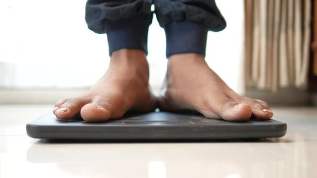 Person stepping onto bathroom scale for weight measurement