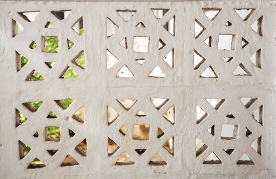 Light-colored breeze block wall with a geometric openwork pattern.