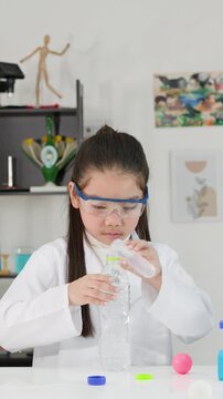 Young Asian Girl Performing Bernoulli's Principle Science Experiment in Classroom