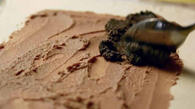 Adding a layer of mushroom pate over the sheet of puffy pastry