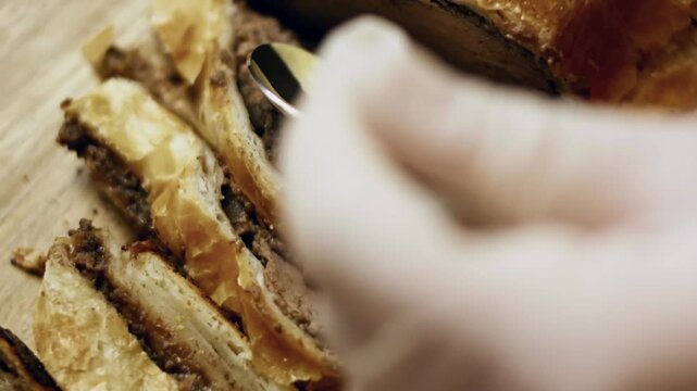 Adding Dijon mustard to a slice of Beef Wellington