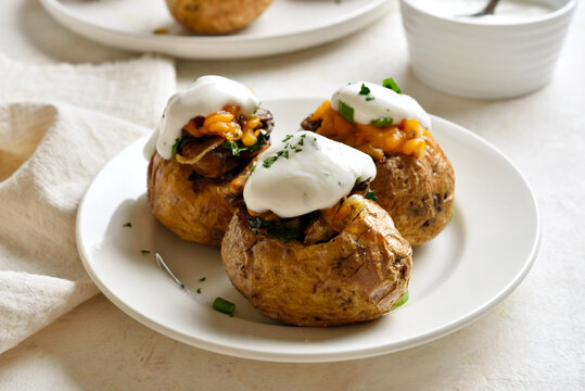 Delicious stuffed baked potatoes with mushrooms, spinach, caramelized onions, cheddar cheese and yogurt based sauce
