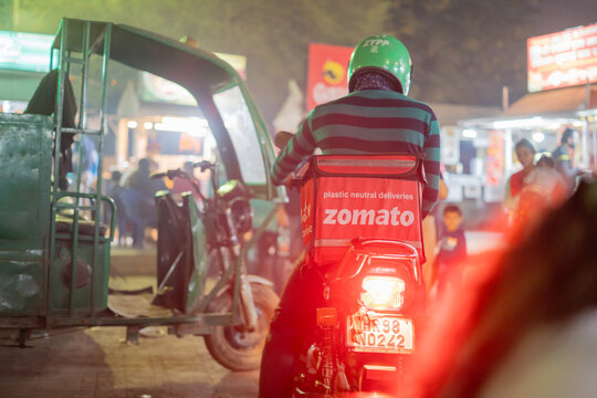 Night shot of food tech delivery startup rider on motorbike stuck in traffic showing the long hours and harsh conditions endured by these gig workers