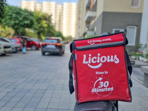 Licious insulated delivery bag mounted on a motorbike in a residential apartment complex, representing Indian meat, chicken and seafood delivery startup offering 30-minute home delivery service.