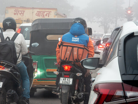 Swiggy Instamart rider driver stuck in a traffic jam on a foggy day showing the challenges faced by these gig workers for hyperlocal quick commerce