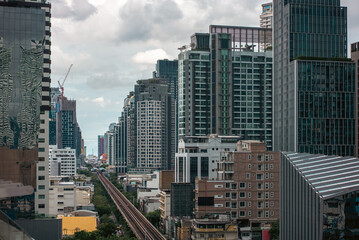 Bangkok skyline with skytrain railway and contrast between modern skyscrapers and old buildings, Elevated rail transit crossing dense cityscape, mix of historic and contemporary towers