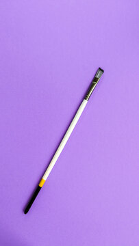 White Wooden Synthetic Paintbrush isolated on Violet Background