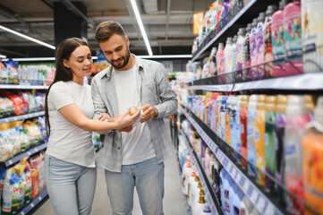 Couple choosing laundry detergent in supermarket aisle