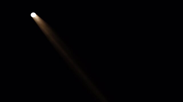 Bright spotlight beam illuminating a dark, empty stage for a dramatic effect.