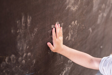 壁に泥の手形をスタンプしている保育園児