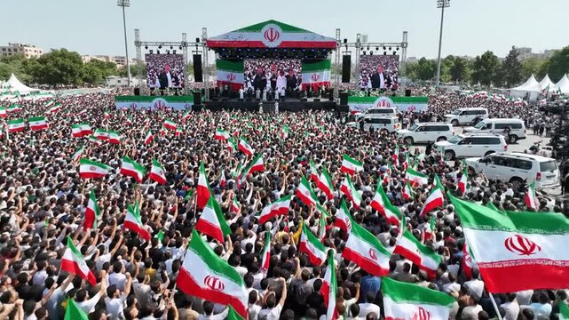Massive crowd waving Iranian flags at outdoor political rally