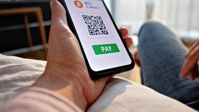 A hand holds a smartphone displaying a QR code for contactless payment, with a PAY button. The scene highlights online shopping and digital finance, emphasizing convenience.