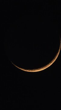 Vertical timelapse of young crescent moon during moonset with moving clouds
