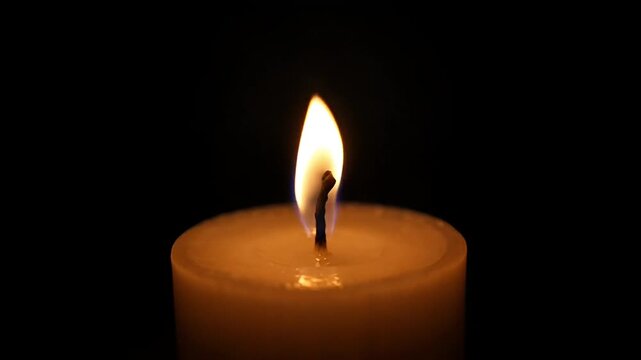 Glowing candle flame in the darkness illuminating hope and peace in remembrance