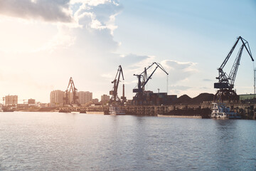 Fototapeta premium Busy cargo port handling shipments between Russia and China with cranes, containers, and vessels. Blagoveshchensk