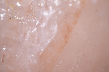 Fototapeta premium Close-up view of translucent pink Himalayan salt crystal with visible texture and mineral inclusions, showcasing natural beauty and unique patterns in a neutral background