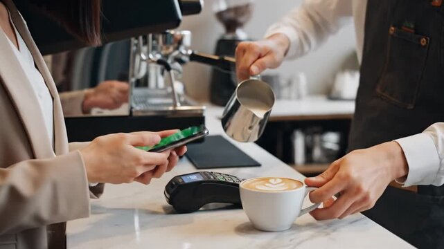 Woman making contactless payment with phone at coffee shop