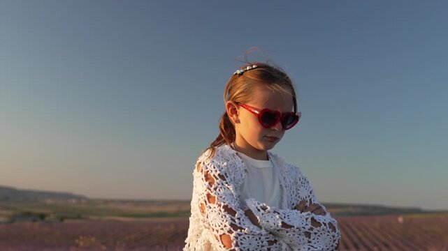 Girl lavender pouting child wearing sunglasses sulks in vast blooming agricultural field during sunset
