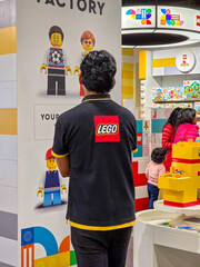 Fototapeta premium Lego store staff member wearing the themed shirt looking at the rush of customers in Delhi's first LEGO store during the opening days