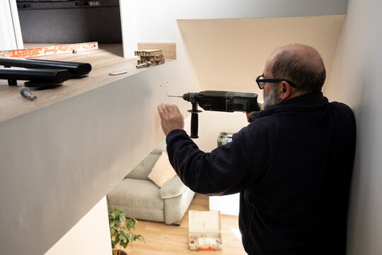 Man drilling a hole into a wall with an electric hammer drill during home improvement