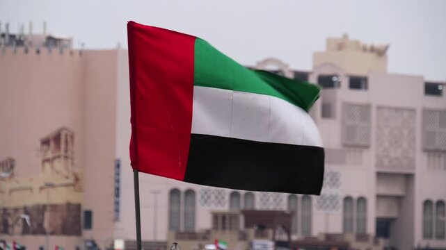 UAE flag waving before Old Dubai buildings in Dubai, United Arab Emirates