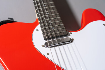 Close-up of a red electric guitar body with white pickguard, chrome hardware, pickups, strings, and part of the neck.