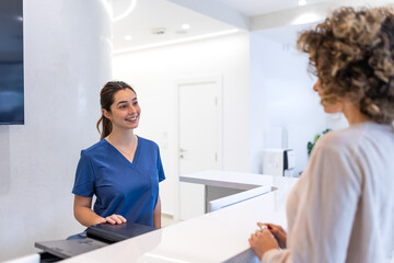 Friendly Medical Receptionist Welcoming Patient at Hospital Front Desk. Smiling Professional in...