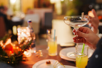 Obraz premium Hand holding a glass at a table with drinks and candles during a gathering