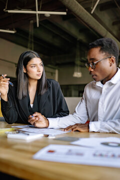 Business meeting between colleagues discussing project plans and strategies at a modern office surrounded by documents with graphics