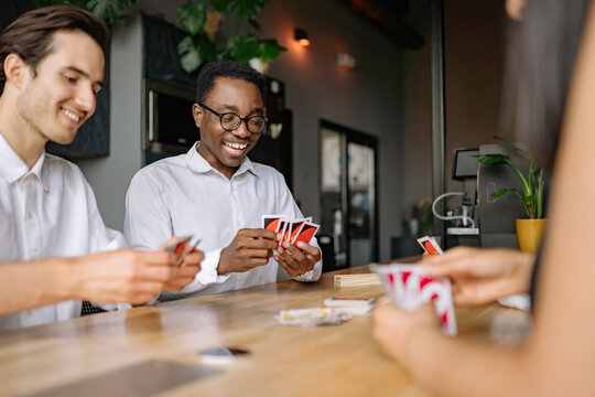 Friends enjoy a spirited card game at a cozy office during a sunny afternoon gathering