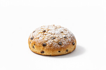Round sweet Easter bread with raisins, almond flakes and powdered sugar on light background, traditional festive pastry, homemade bakery concept.