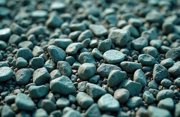 Close up of textured green gravel and stones scattered outdoors. Natural material forms a rough surface. Sunlight creates shadows on the earthy ground, ideal for design.