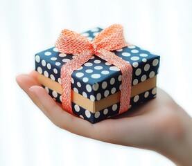 hand gently offering a small navy polka dot gift box with white dots, beige band and orange patterned ribbon bow, soft pastel background conveying thoughtful surprise and joy