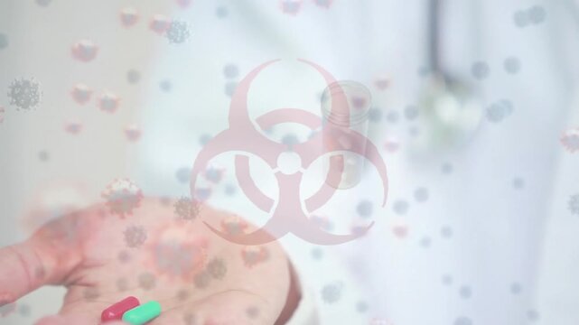 Animation of biohazard symbol and covid-19 cells against mid section of doctor holding medical pills