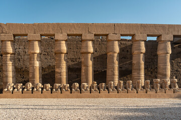 Fototapeta premium Row of ram-headed sphinxes under a massive stone colonnade at Karnak Temple Complex, Luxor, Egypt