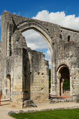 Historic stone ruins of the Prieur&eacute; Saint-Cosme near Tours, France. The ancient monastic architecture features a prominent gothic arch and weathered walls under a blue sky with soft white clouds