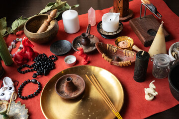 Fototapeta premium Various spiritual and ritualistic items arranged on a red cloth for meditation and practicing magic