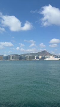 Victoria Harbour, Kowloon, Hong Kong- 15 Feb 2026: vertical video of Skyline of Victoria Harbour showing Kai Tak, Mong Kok, Kai Tak Pier and Ho Man Tin, with blue sky and sea
