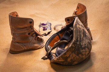 Scattered on the sands of time, the soldier’s gear stands as a tribute to bravery and loss, blending with the desert wind that carries forgotten echoes of war. Silent Memories of War. © Narong Niemhom