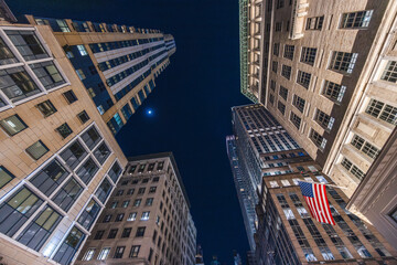 Night view of Manhattan skyscrapers with American flag from street perspective in New York City