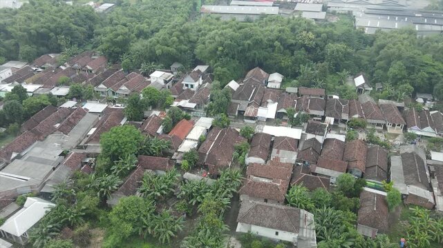 Aerial 4K view of a densely populated rural village surrounded by lush green trees in Indonesia