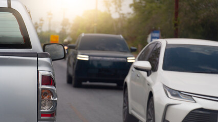 Rear side of pickup truck car driving on asphalt road. A sedan coming from the opposite direction drove past. Background blurred of trees and light shining from behind.