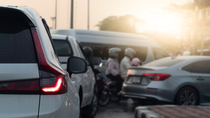 Obraz premium Abstract rear side view of white car open light brake. Front of car several cars prepare in a U-turn area. Traffic is congested during rush hour with both cars and motorcycles going to work or school.