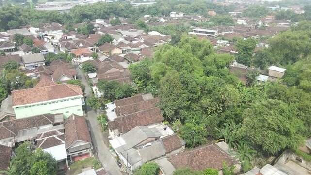 Aerial 4K view of a densely populated rural village surrounded by lush green trees in Indonesia