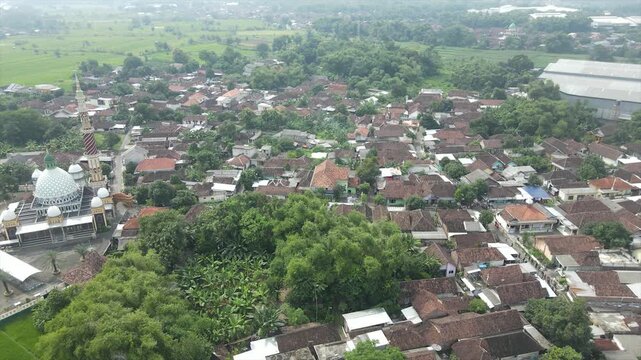 Aerial 4K view of a densely populated rural village surrounded by lush green trees in Indonesia